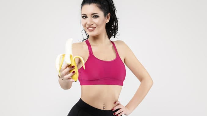 Attractive fit woman eating banana, isolated on Background.