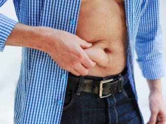 man wearing a blue and white checkered shirt is pinching his belly fat with his right hand