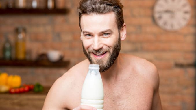 Muscular man drinking milk from the bottle on the kitchen