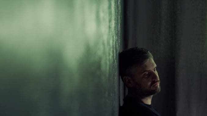 Lonely man sitting alone in gloomy room