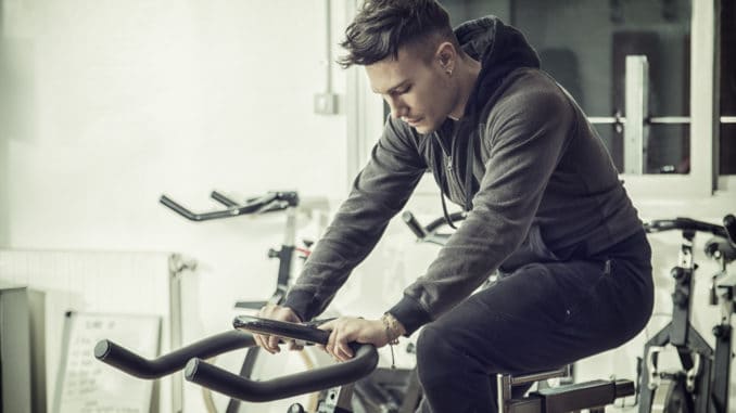 dreamstime_m_87805473 Attractive young man exercise in gym: spinning, exercising on stationary bike