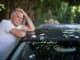 Tensed senior man with head in hand leaning on car