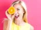 Happy young woman holding oranges halves on a pink background