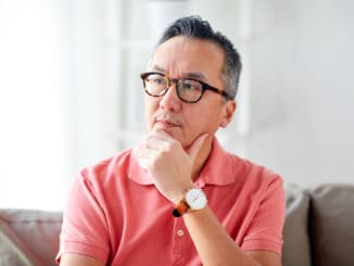 People concept - asian man thinking at home