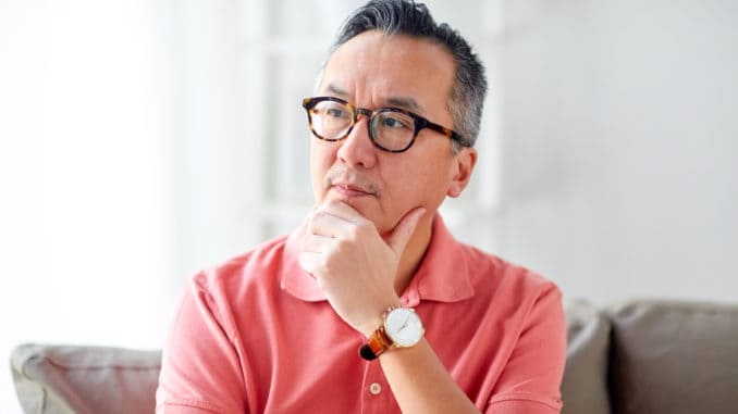 People concept - asian man thinking at home