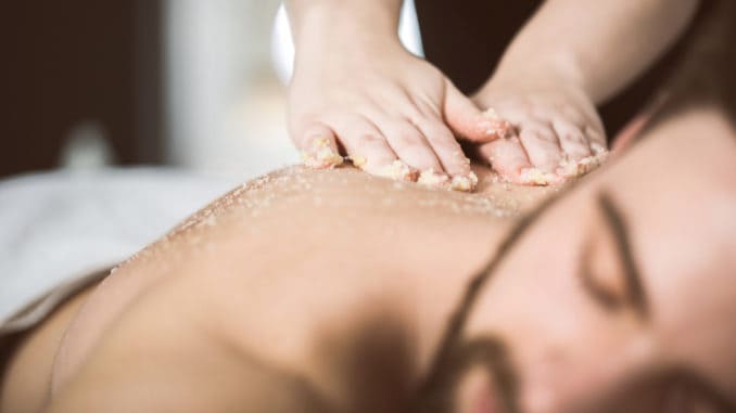 Man at beautician`s getting an exfoliating massage with salt peeling