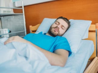 Young sick man sleeping on hospital bed at ward