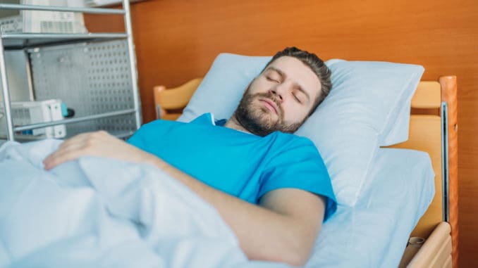 Young sick man sleeping on hospital bed at ward