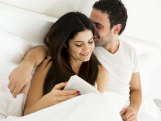 Young couple reading a book in the bed
