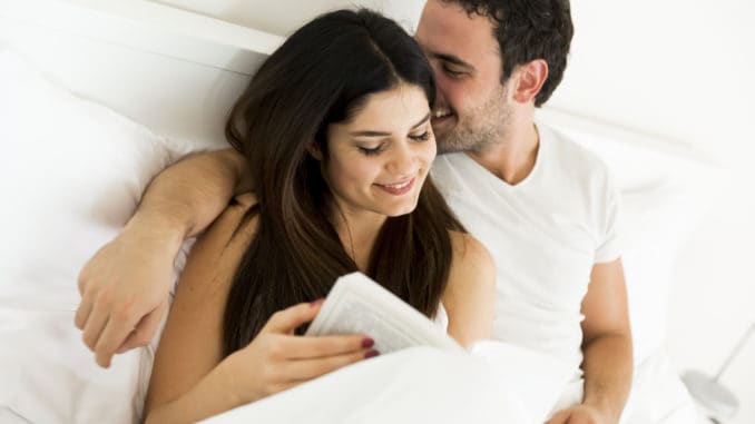 Young couple reading a book in the bed