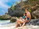 Young couple in bathing suits on rocks on a tropical island. Summer vacation concept.