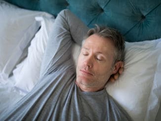 Man sleeping on bed in bedroom at home