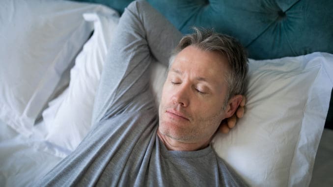 Man sleeping on bed in bedroom at home