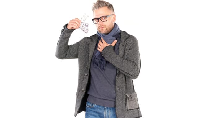 dreamstime_m_97614273 man wearing warm scarf and holding pills