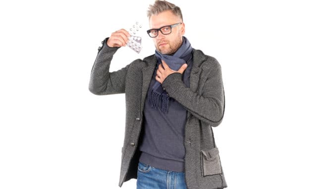 man wearing warm scarf and holding pills