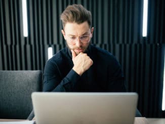 Shot of young man sitting at table looking away and thinking. Thoughtful businessman sitting office.