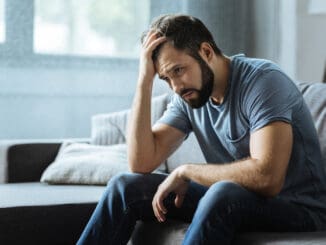 Sad gloomy cheerless man holding his forehead