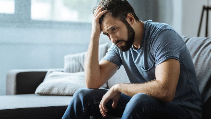 Sad gloomy cheerless man holding his forehead