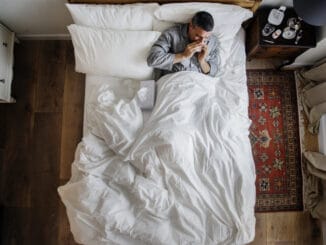 Sick man on the bed blowing his nose