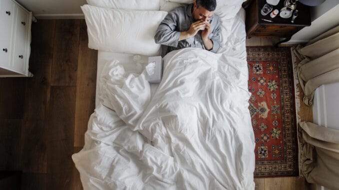 Sick man on the bed blowing his nose