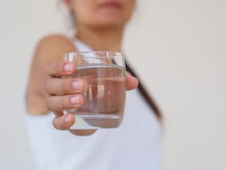 A glass of clean mineral water in woman`s hands.