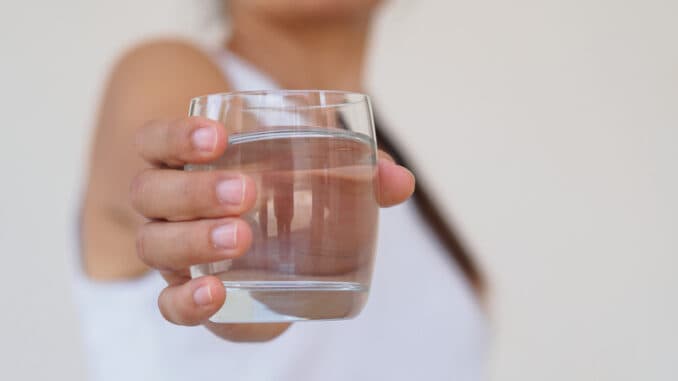 A glass of clean mineral water in woman`s hands.