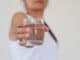 A glass of clean mineral water in woman`s hands.