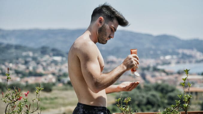 Shirtless Young Man Putting on Sunscreen Cream