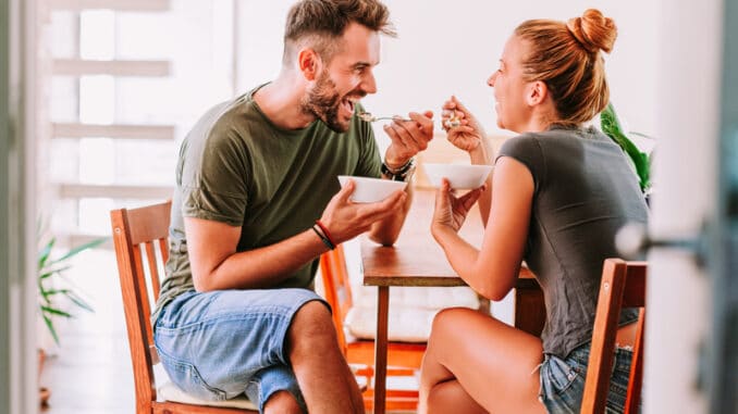 Young couple eating cereal breakfast at dining room table