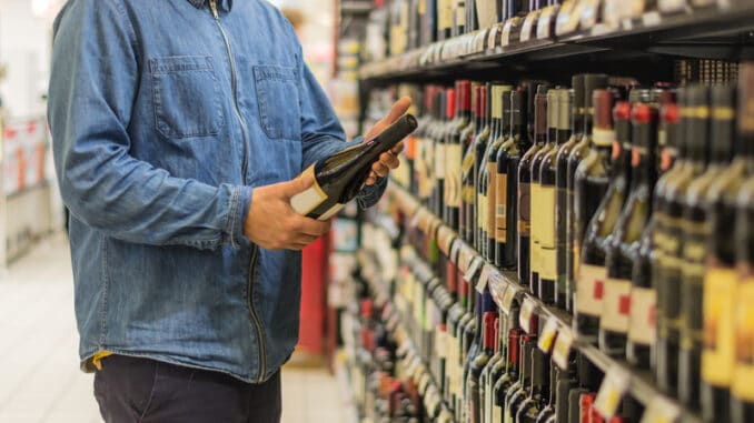 Man is buying a bottle of wine at the liquor market