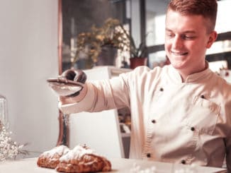 Adding sugar powder. The confectioner adding sugar powder to the fresh bakery