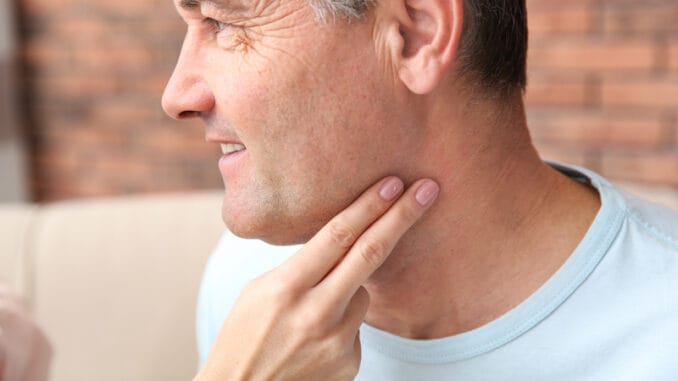 Young woman checking mature man`s pulse with fingers indoors