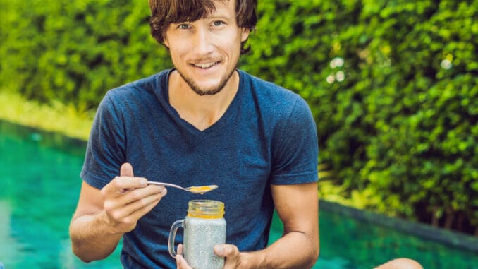 Man eat dessert with chia seeds and mangoes by the pool in the morning.