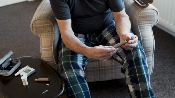 Close up shot of a diabetic man using an insulin pen at home