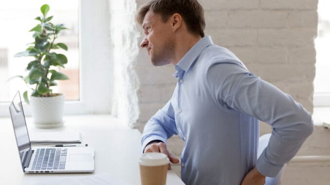 dreamstime_s_139857659 Unhealthy office worker sitting at desk opposite computer feels sudden sharp pain in lower back.
