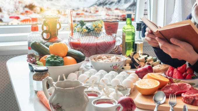 Man reading book with preparing food on dining table with snowing on village in wintertime