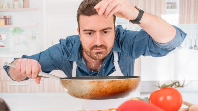 Cheerful young man preparing food at home