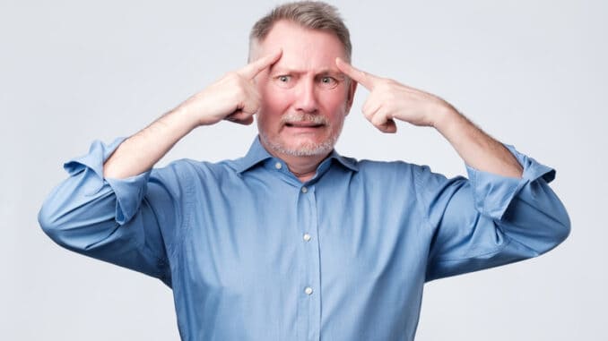 Mature european man holds fingers on temples