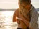 Happy romantic couple in embrace and hug on beach at a sunny day.