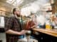 Close-up shot of a stylish bearded adult guy smoking hookah indoor of a cafe