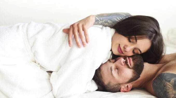 couple in love smiling while lying on bed together