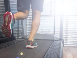 Legs of a running man on a treadmill in a sunny morning