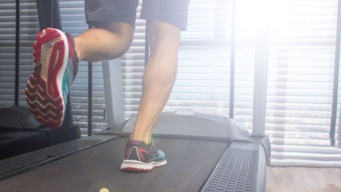 Legs of a running man on a treadmill in a sunny morning