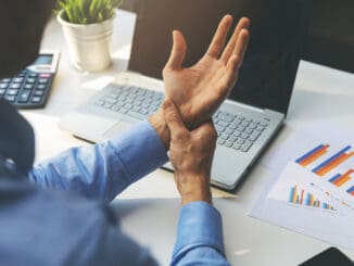 man suffering from wrist joint pain while working on laptop