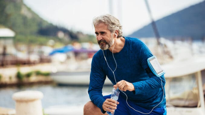 dreamstime_s_159592148 Fit thirsty senior man drinking water before running.