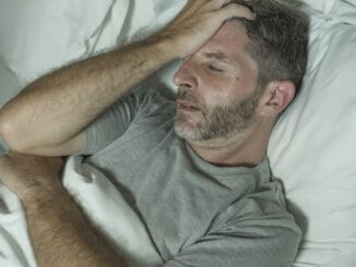 Dramatic portrait of stressed and frustrated man in bed