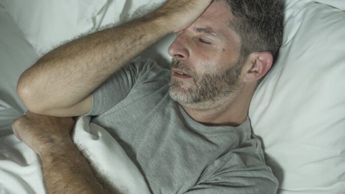 Dramatic portrait of stressed and frustrated man in bed