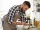 Young man cooking tasty cream soup with mushrooms