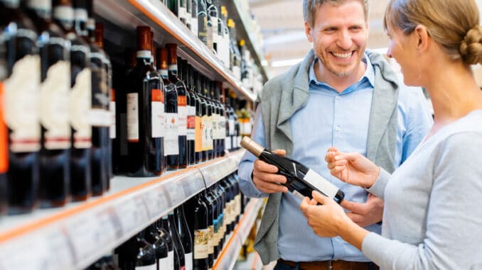 Woman and man buying red wine in supermarket