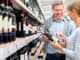 Woman and man buying red wine in supermarket